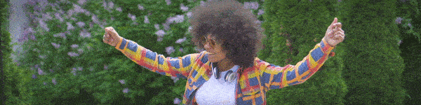 Energetic young woman smiling and dancing along a sidewalk